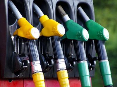 Gekleurde benzinepompen hangen aan een rood tankstation, klaar voor gebruik.