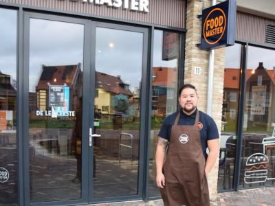 Man in Foodmaster-voorschort staat voor de ingang van de nieuwe Foodmaster De Draai locatie.