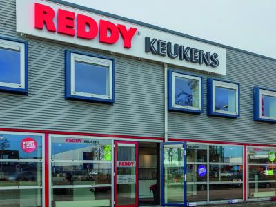 Voorkant van het nieuwe Reddy Keukens filiaal in Lelystad met opvallende rode en witte gevelreclame.
