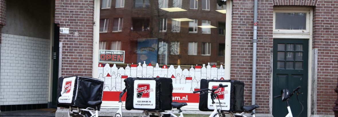 Voorgevel van Pizzadam met drie bezorgfietsen geparkeerd op de stoep ervoor.